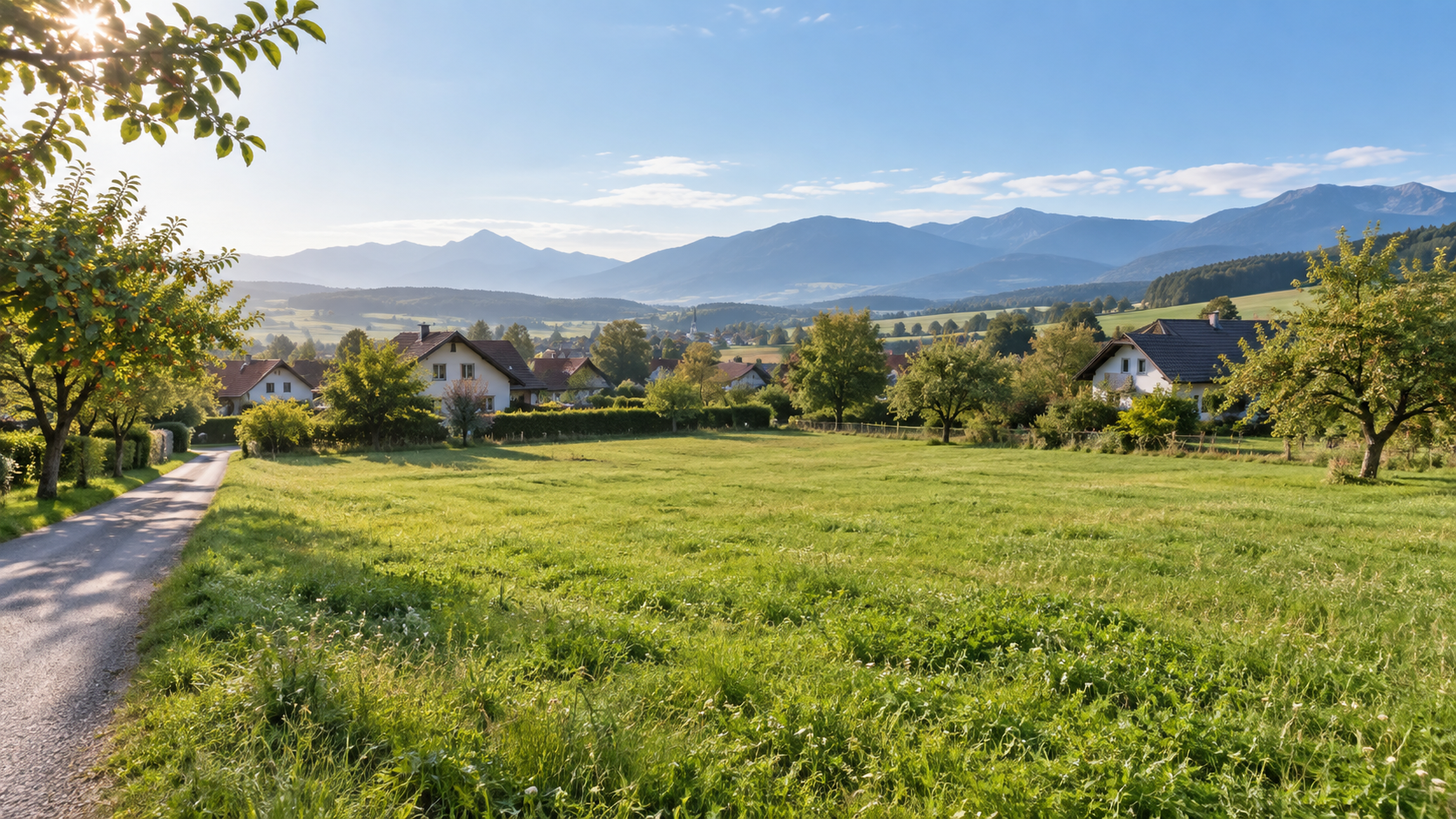 Freie grüne Fläche am Rand eines österreichischen Ortes mit Häusern und Bergen